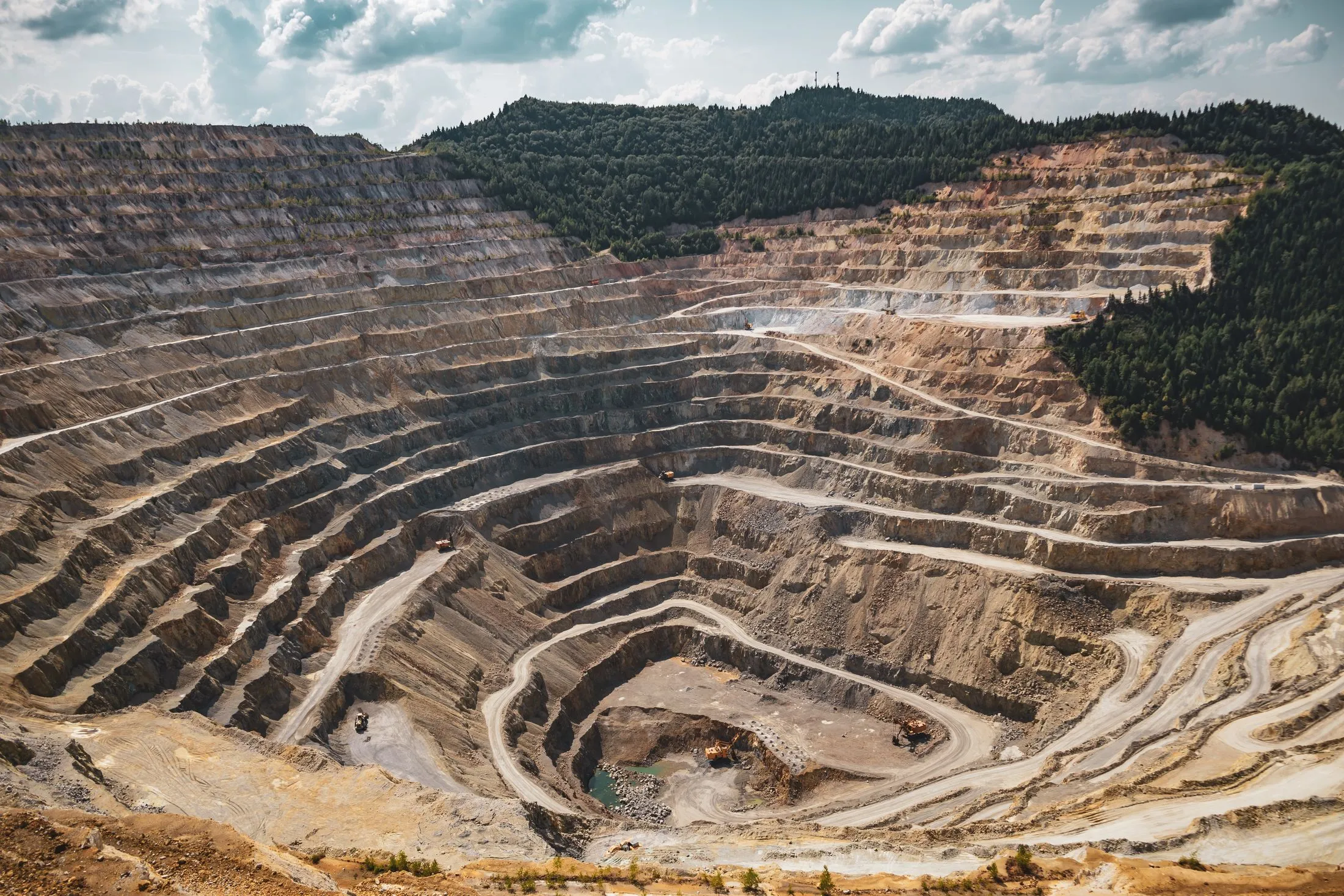 Aerial view of a terraced mine ringed by forest